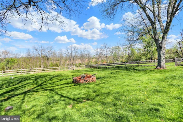view of yard with fence, an outdoor fire pit, and a rural view