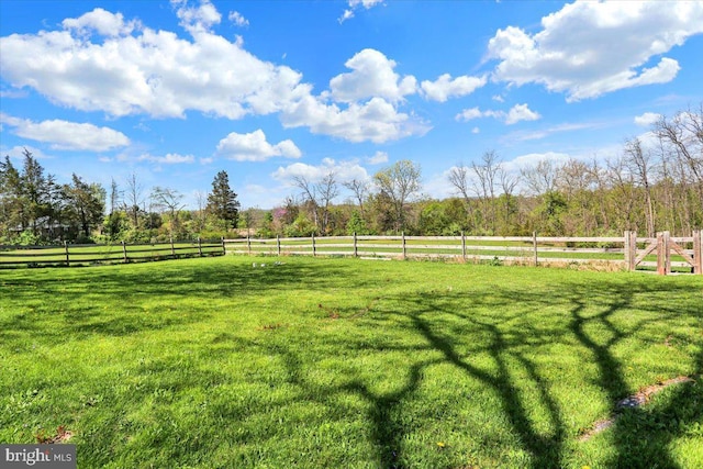 view of yard with fence and a rural view