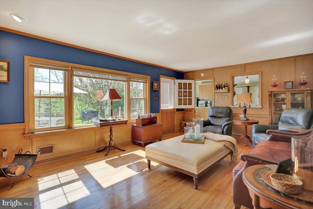 living area featuring light wood-style floors, wainscoting, and visible vents