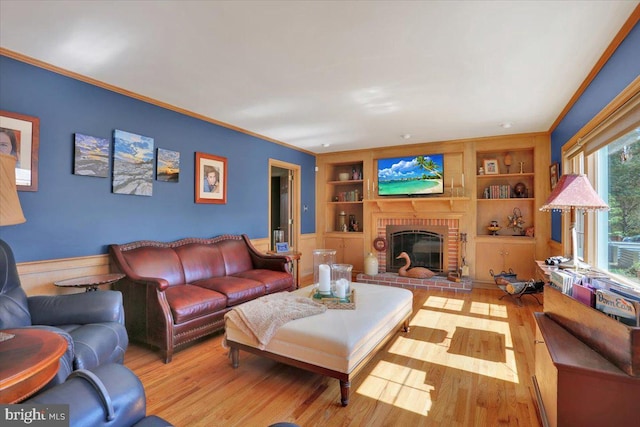 living area featuring built in features, ornamental molding, a fireplace, and wood finished floors