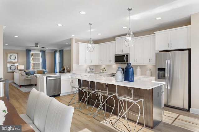 kitchen featuring light countertops, appliances with stainless steel finishes, white cabinetry, and open floor plan