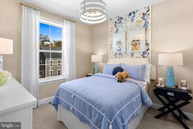 carpeted bedroom featuring baseboards and a chandelier