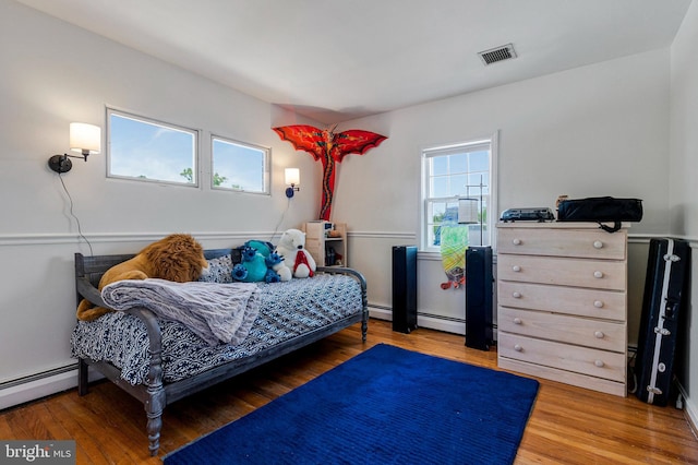 bedroom with visible vents, a baseboard radiator, and wood finished floors
