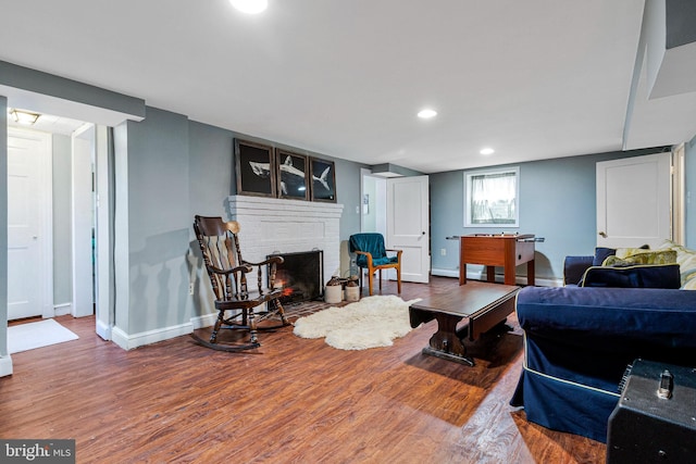 living room featuring baseboards, a fireplace, recessed lighting, and wood finished floors