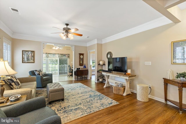 living area featuring visible vents, a ceiling fan, and ornamental molding