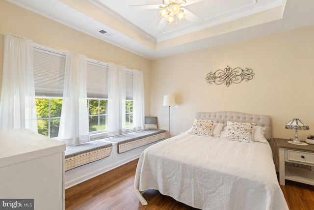 bedroom featuring ornamental molding, visible vents, ceiling fan, dark wood-style floors, and a raised ceiling