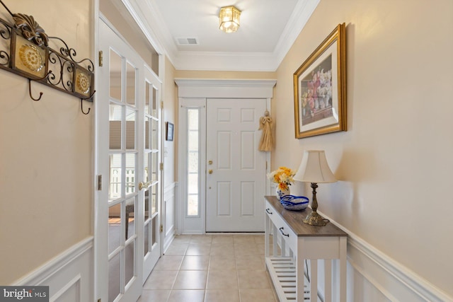 foyer with french doors, visible vents, crown molding, light tile patterned floors, and wainscoting