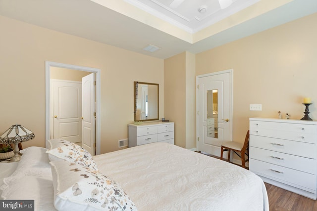 bedroom with ornamental molding, visible vents, and wood finished floors