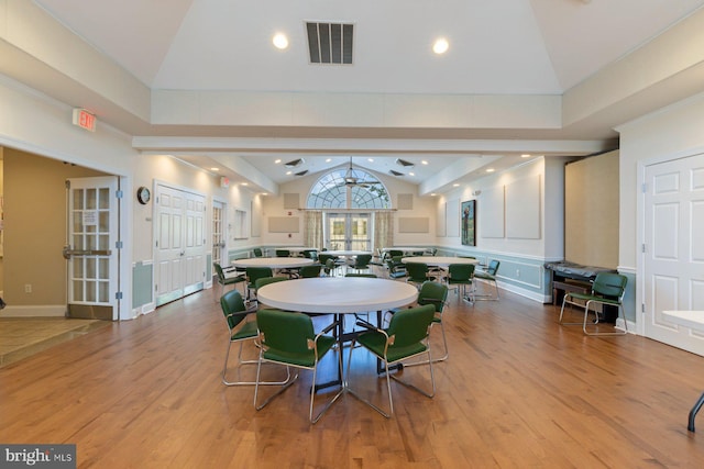 dining room featuring vaulted ceiling, wood finished floors, and visible vents