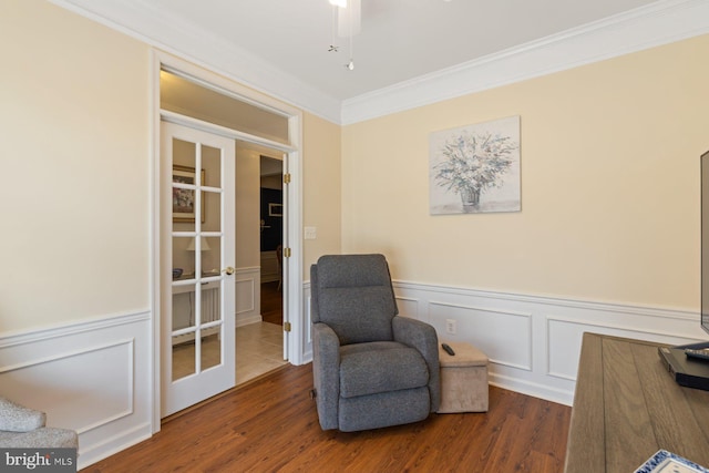 living area featuring wainscoting, ornamental molding, and wood finished floors