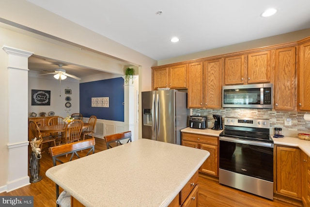 kitchen featuring brown cabinetry, stainless steel appliances, light countertops, and a ceiling fan