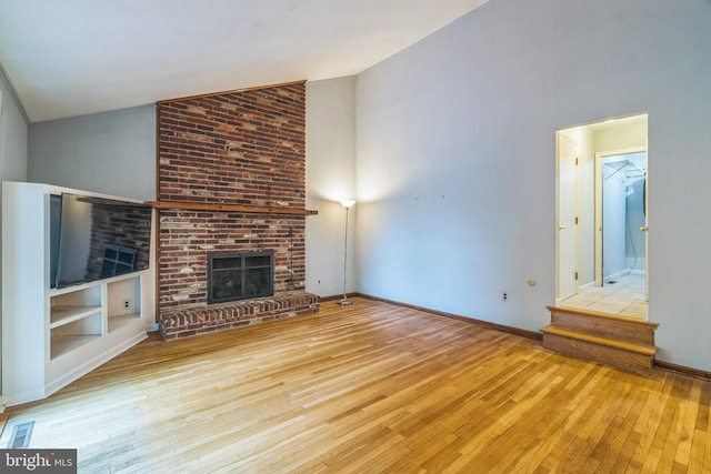 755 Shawmont Ave, Philadelphia, PA 19128 - unfurnished living room with wood-type flooring, a fireplace, high vaulted ceiling, and baseboards