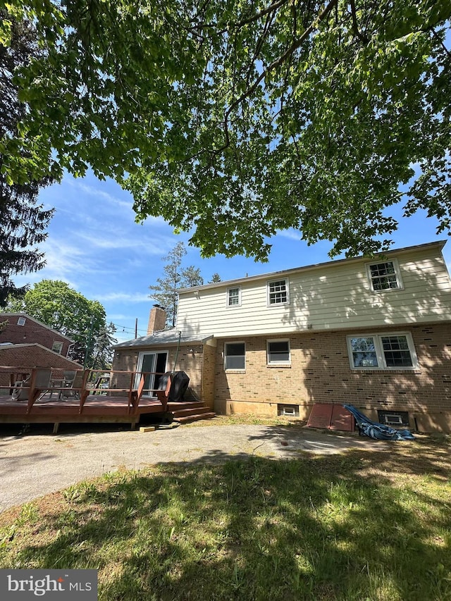 755 Shawmont Ave, Philadelphia, PA 19128 - rear view of house with a wooden deck, brick siding, a yard, and a chimney