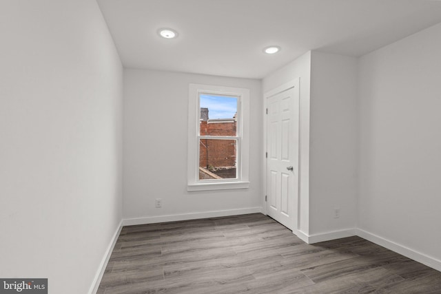 empty room featuring baseboards, recessed lighting, and wood finished floors