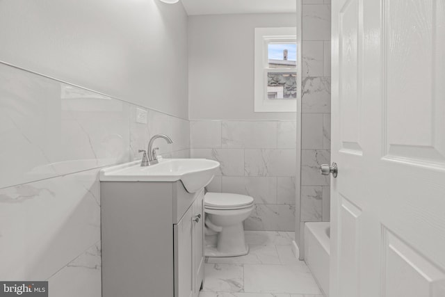full bath featuring toilet, a wainscoted wall, tile walls, marble finish floor, and vanity