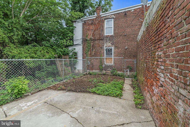 view of side of home featuring brick siding, a patio area, and fence