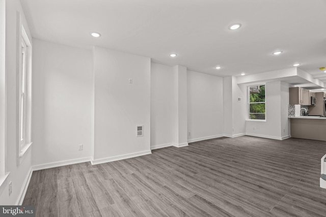 unfurnished living room with dark wood-style flooring, baseboards, visible vents, and recessed lighting