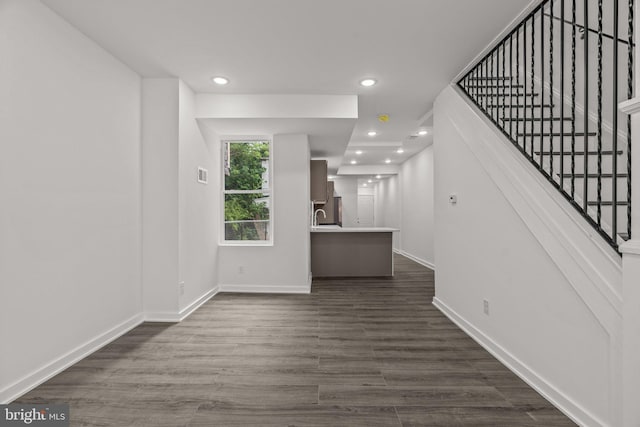 unfurnished living room featuring dark wood finished floors, stairs, baseboards, and recessed lighting