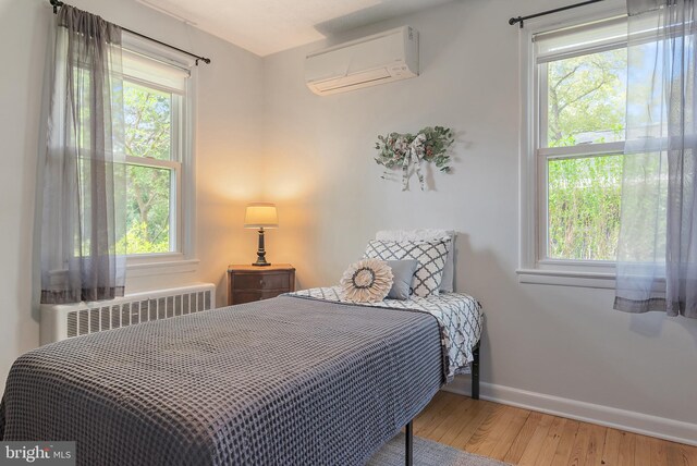 111 Linden Ave, Pasadena, MD 21122 - bedroom featuring an AC wall unit, baseboards, wood finished floors, and radiator