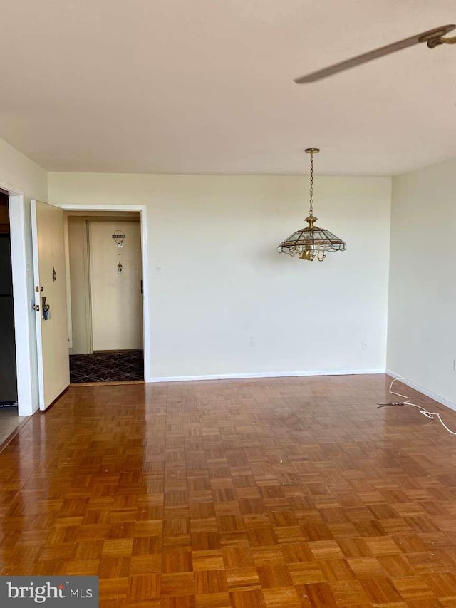 spare room with baseboards and a chandelier