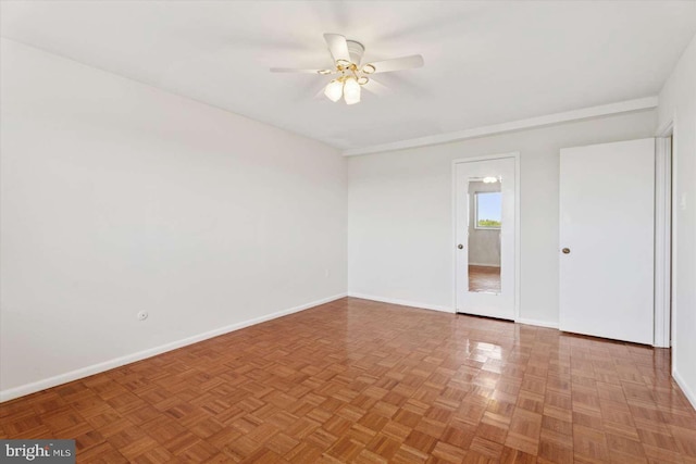 spare room with a ceiling fan and baseboards