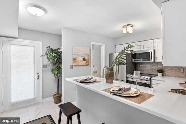 kitchen featuring decorative backsplash, light countertops, white cabinets, marble finish floor, and stainless steel appliances
