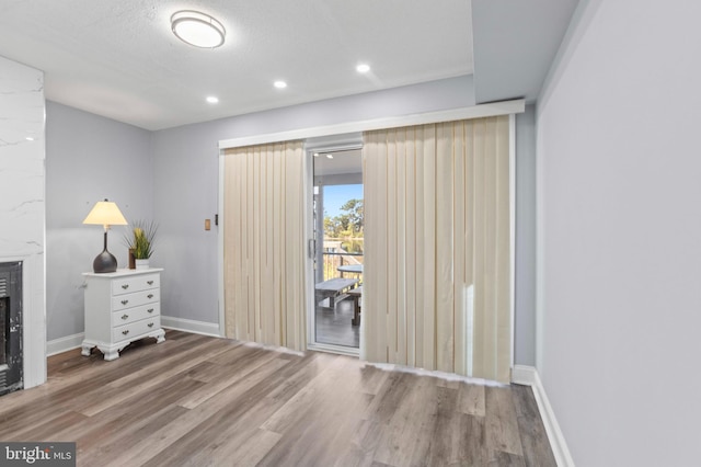 unfurnished bedroom featuring baseboards, access to outside, a fireplace, and wood finished floors