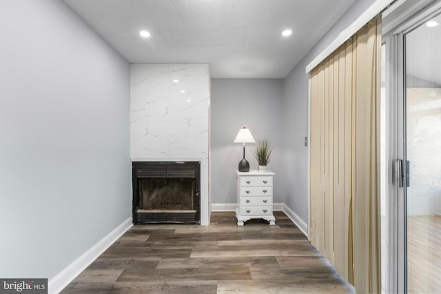 unfurnished living room with a large fireplace, baseboards, recessed lighting, and wood finished floors