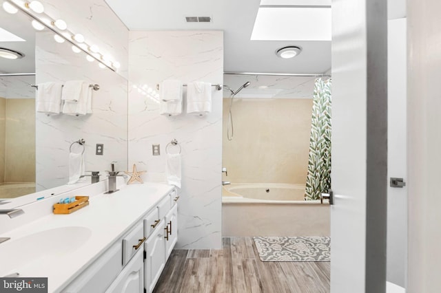 bathroom featuring a sink, shower / tub combo, wood finished floors, and visible vents