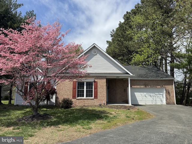 view of front of home featuring brick siding, an attached garage, aphalt driveway, and a front yard