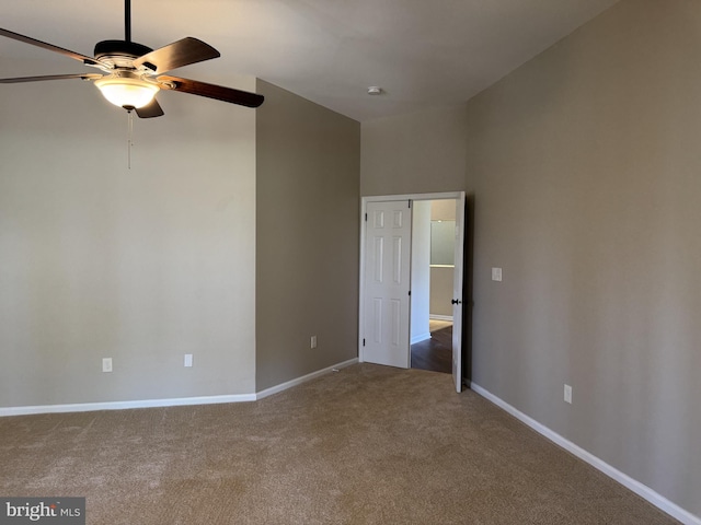 carpeted spare room featuring baseboards and ceiling fan