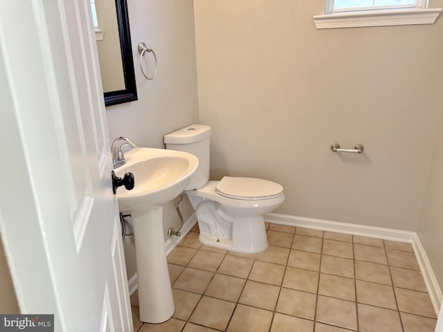 bathroom with baseboards, tile patterned floors, and toilet