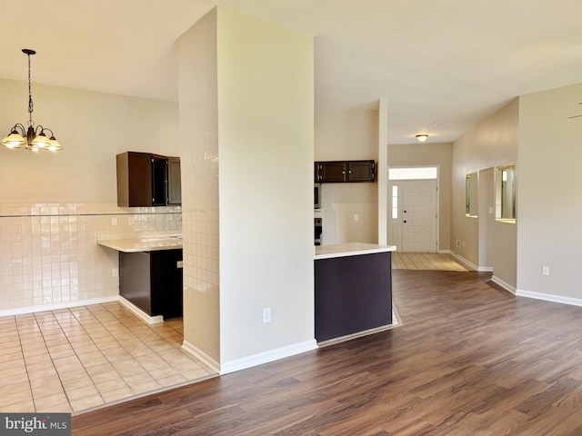 kitchen featuring dark brown cabinets, light countertops, a chandelier, decorative light fixtures, and dark wood-type flooring