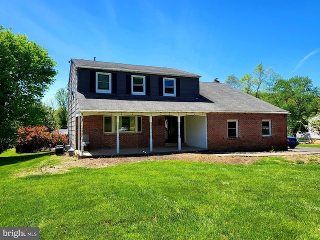 traditional home featuring brick siding, a patio, and a front lawn