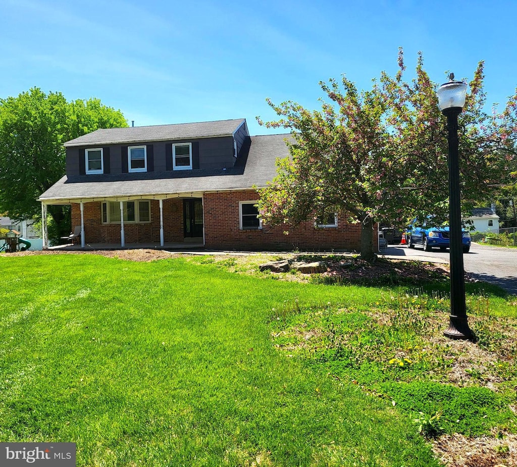 view of front of home with covered porch, brick siding, and a front lawn