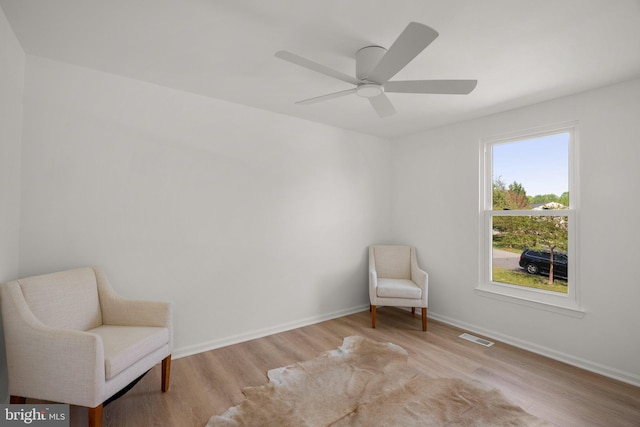 living area with baseboards, ceiling fan, visible vents, and wood finished floors