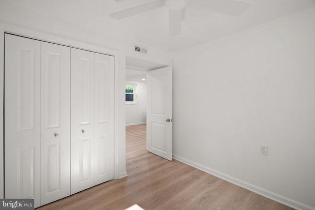 unfurnished bedroom featuring ceiling fan, visible vents, light wood-type flooring, baseboards, and a closet
