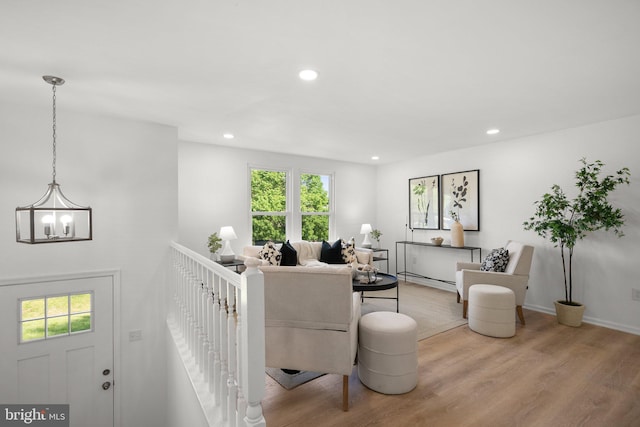 living room featuring plenty of natural light, recessed lighting, light wood-style floors, and a notable chandelier
