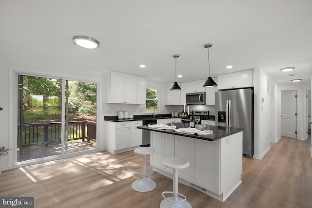 kitchen with a sink, dark countertops, light wood-style floors, and stainless steel appliances