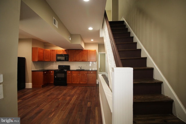 interior space featuring a sink, black appliances, dark wood-type flooring, visible vents, and dark countertops