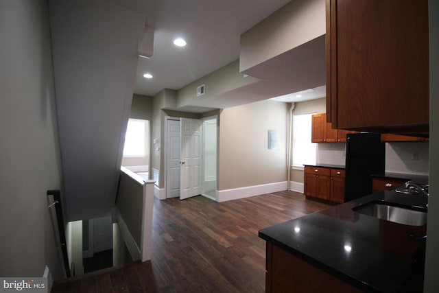 kitchen featuring baseboards, dark wood finished floors, visible vents, a sink, and dark countertops