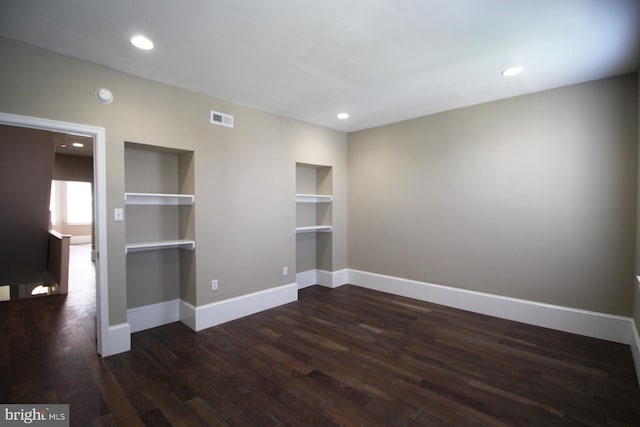 spare room with dark wood-type flooring, visible vents, recessed lighting, built in features, and baseboards