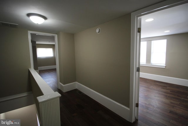 hall with dark wood-type flooring, baseboards, visible vents, and recessed lighting