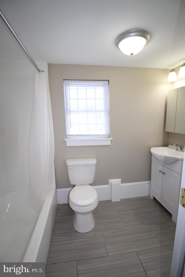 full bathroom with baseboards, shower / bath combo with shower curtain, vanity, and toilet