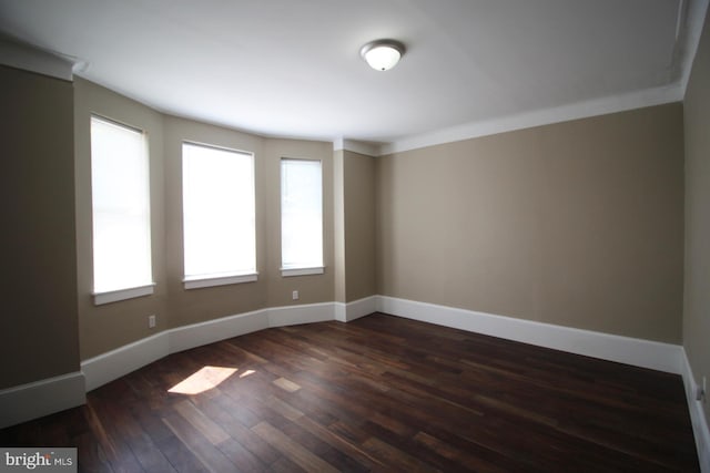 unfurnished room with baseboards and dark wood-style floors