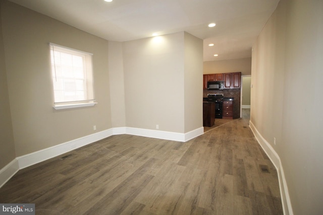 empty room featuring dark wood-style flooring, baseboards, visible vents, and recessed lighting