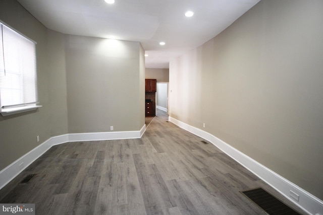 empty room featuring visible vents, wood finished floors, baseboards, and recessed lighting