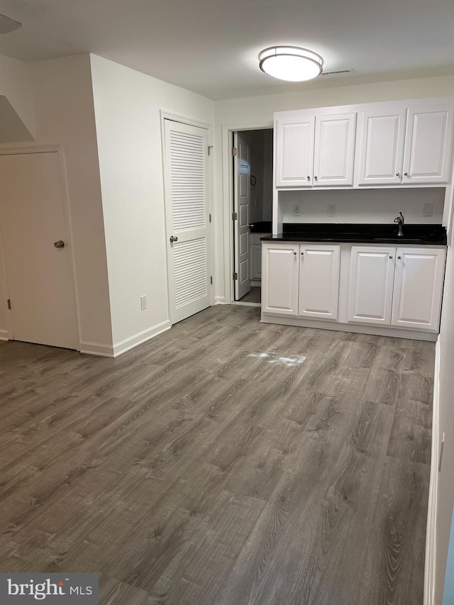 5849 Colfax Ave, Alexandria, VA 22311 - kitchen featuring white cabinets, wood finished floors, dark countertops, a sink, and baseboards