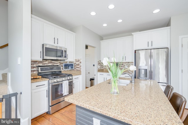 109 Manila Pl, Stephenson, VA 22656 - kitchen with stainless steel appliances, a sink, white cabinetry, a kitchen breakfast bar, and light stone countertops