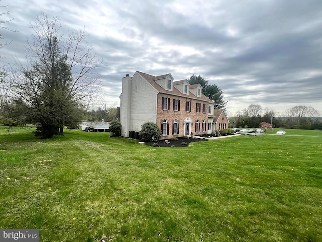 view of side of property with a chimney, a yard, and brick siding